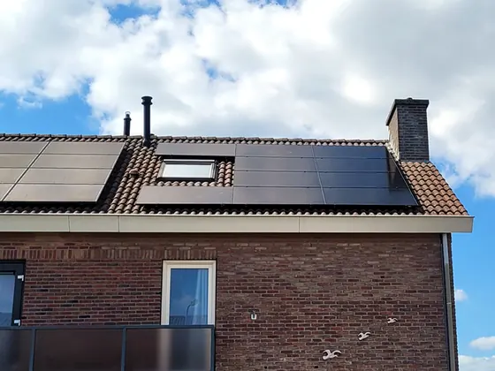 Zwarte zonnepanelen op het schuine dak van een bakstenen woning