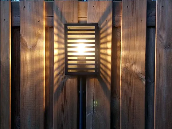 Brandende buitenlamp op een houten schutting in de avond
